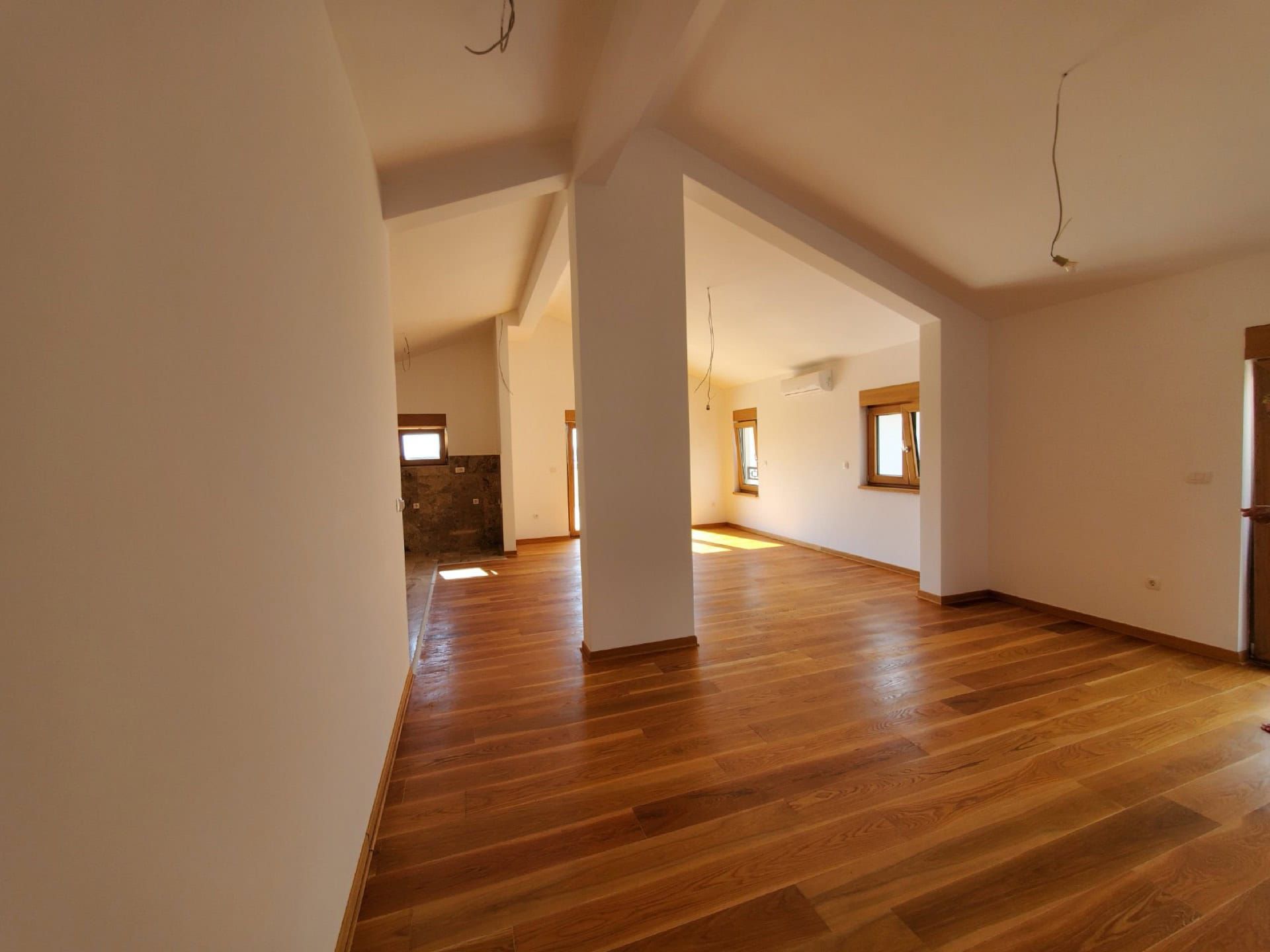 Spacious living room in a penthouse in Pržno, Montenegro: bright interior, wooden floor, and panoramic windows.