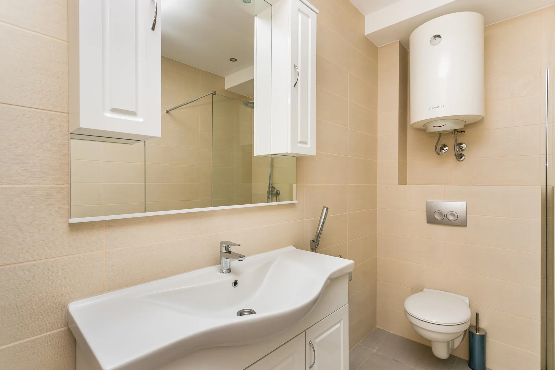 Modernes Badezimmer im Penthouse, Rafailovici, Montenegro: weiße Sanitäranlagen, Duschkabine und Ariston-Boiler.