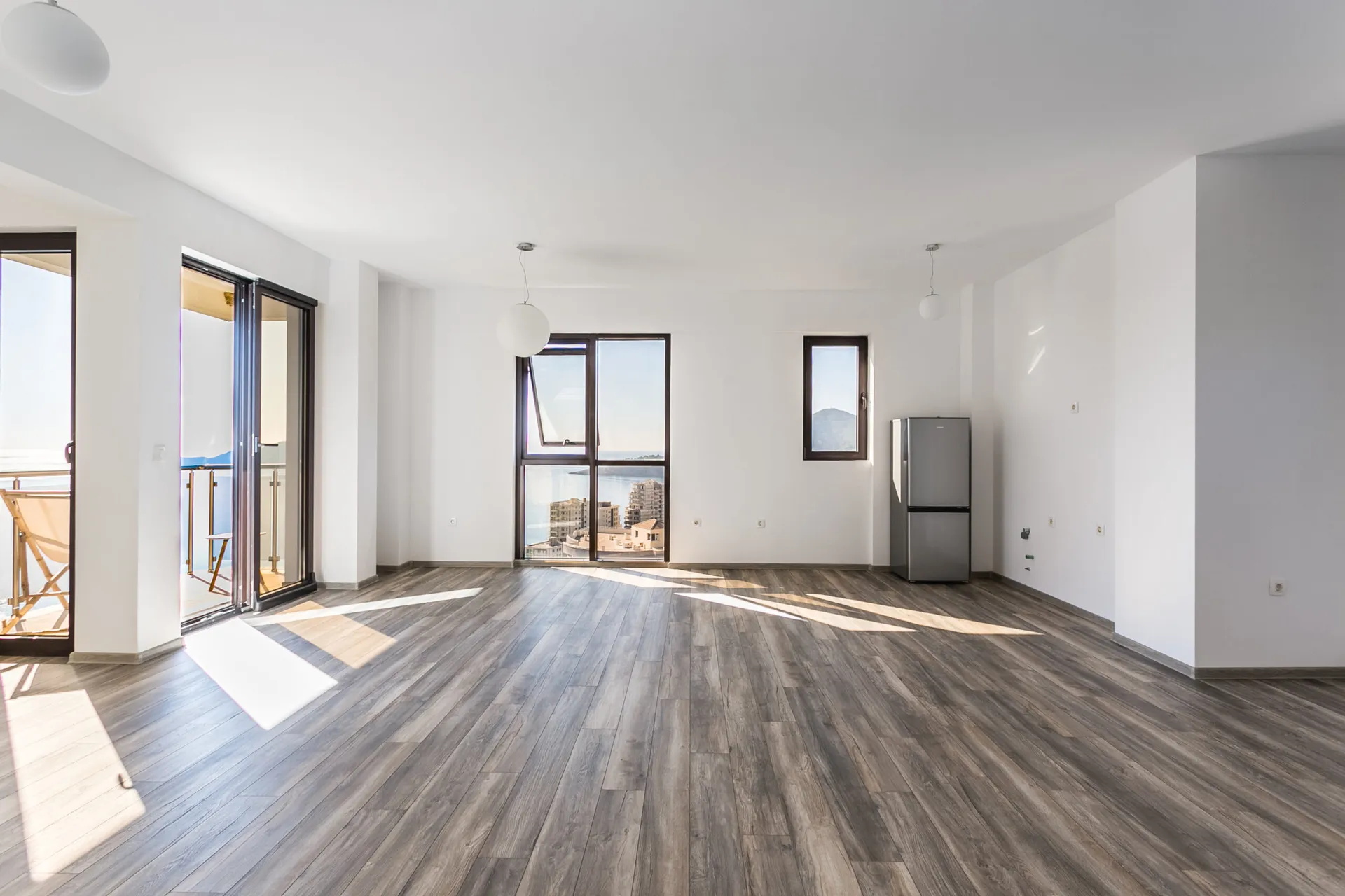Helles Wohnzimmer im Penthouse in Rafailovici, Montenegro, mit Panoramablick auf das Meer und Zugang zum Balkon.