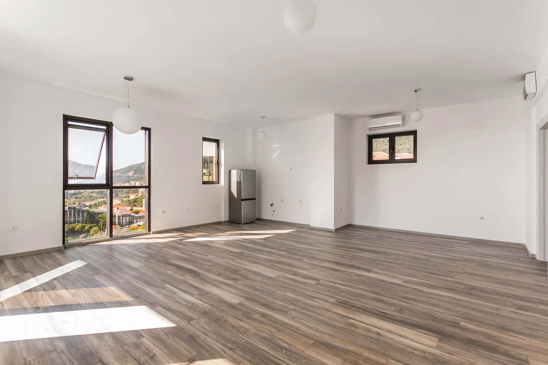 Helles Wohnzimmer im Penthouse, Rafailovići, Montenegro: Panoramafenster mit Meerblick, Laminatboden und Klimaanlage.