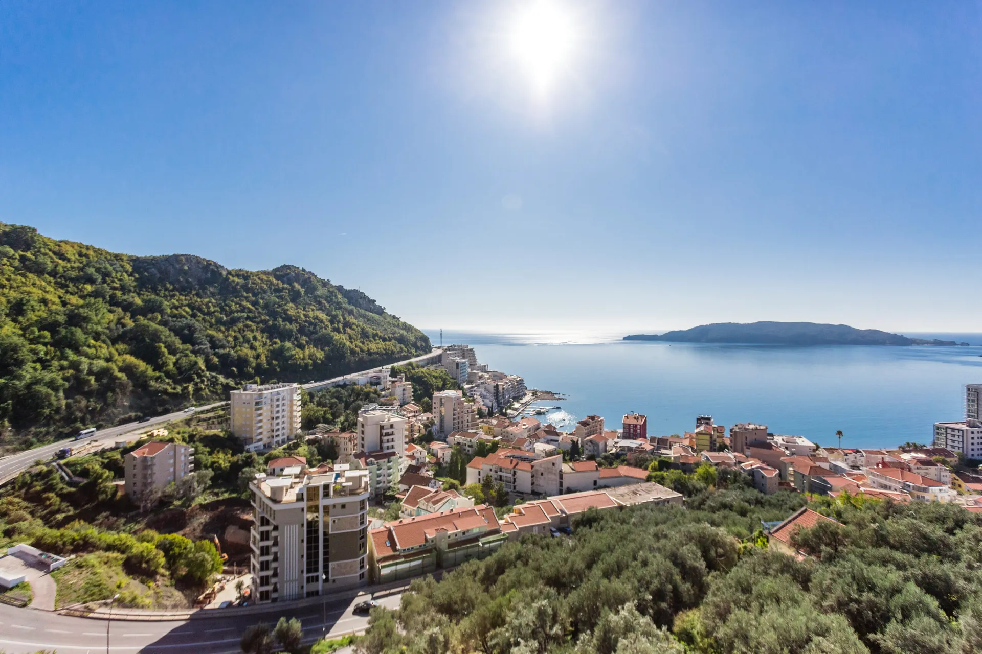 Panoramablick auf das Meer und den Ferienort Rafailovići, Budva-Riviera, Montenegro: städtische Bebauung und grüne Hügel.