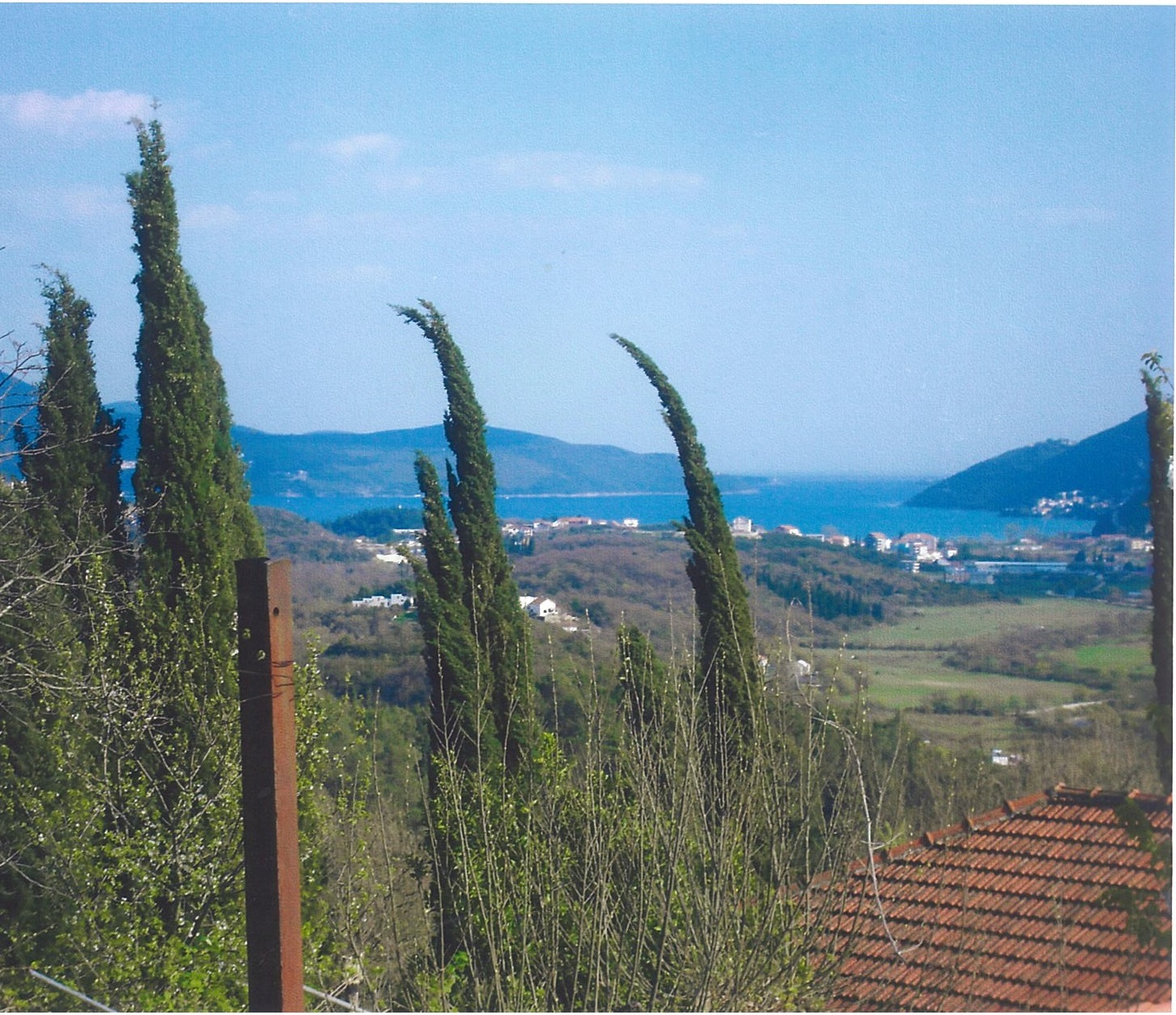Panoramski pogled na more i planine sa zemljišta u Lučićima, Herceg Novi, Crna Gora: čempresi i krov od crepa.