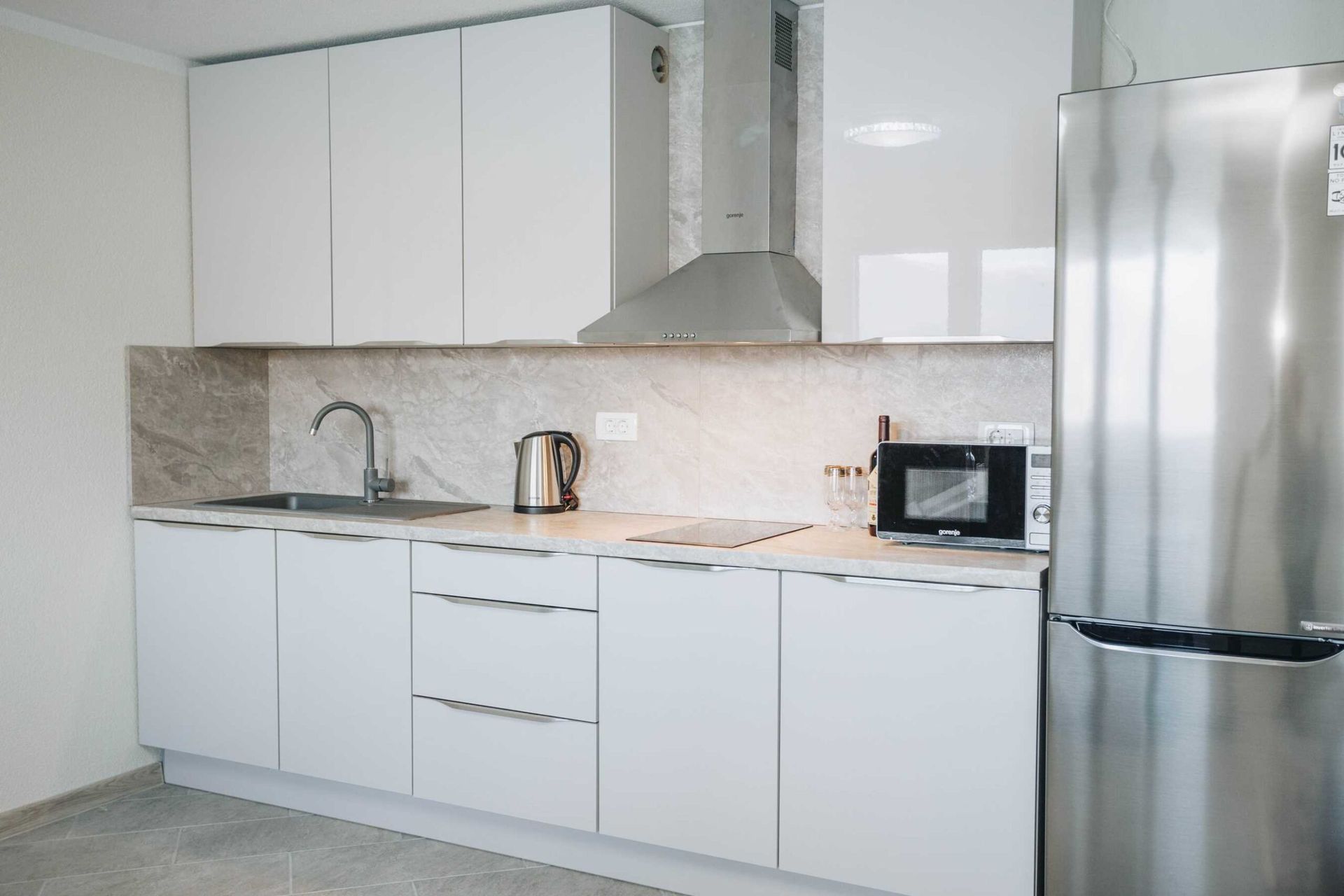 Nowoczesna biała kuchnia ze sprzętem Gorenje w apartamencie w willi w Krašići, Czarnogóra.