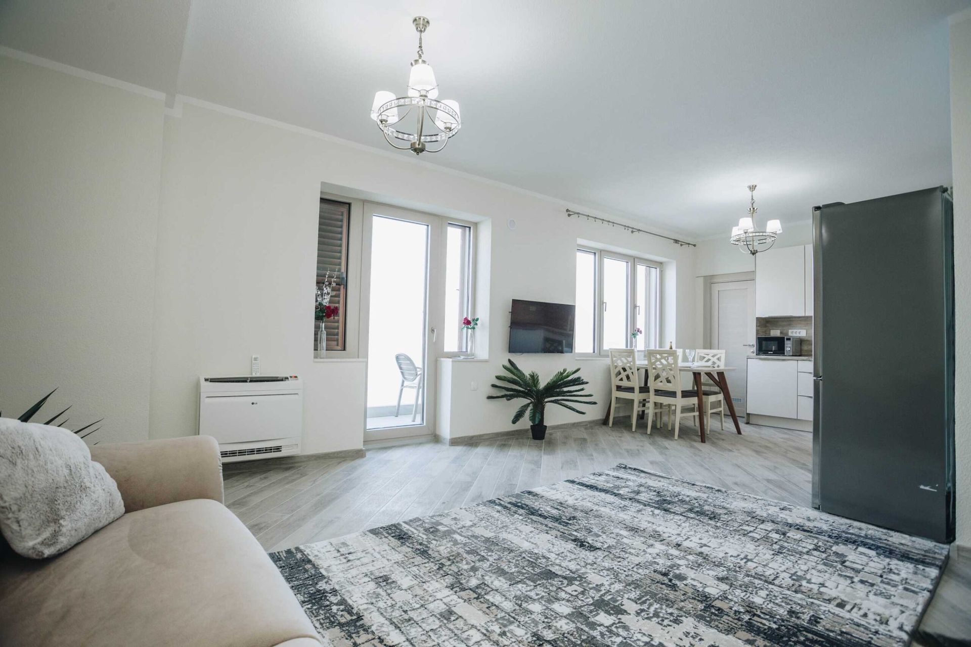 Jasny salon z kuchnią w willi w Krašići, Czarnogóra: nowoczesne meble, dywan, wyjście na taras i widok na morze.