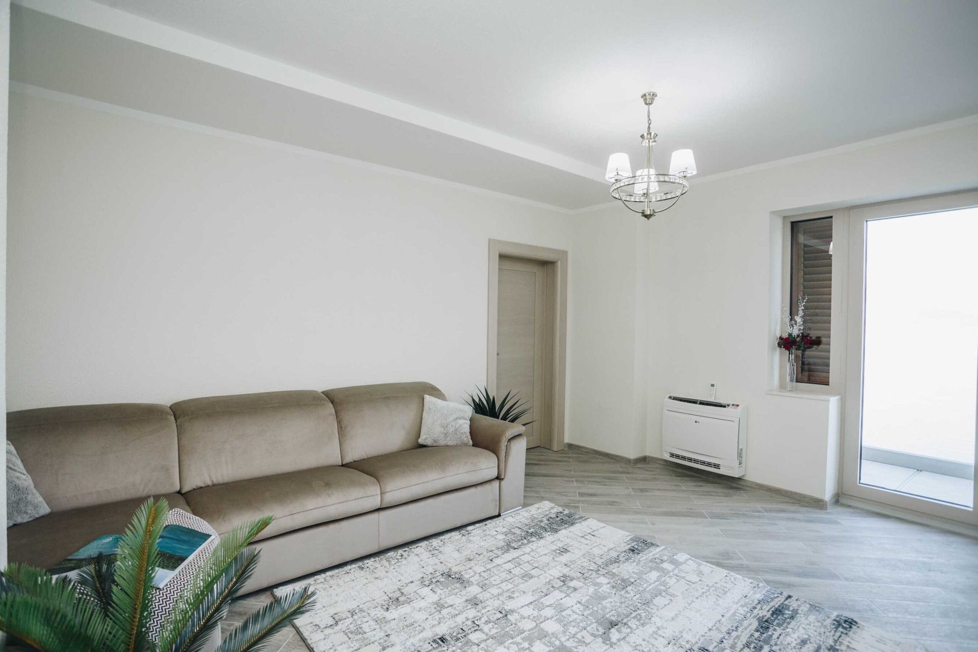Jasny salon z beżową sofą, dywanem i wyjściem na taras w willi w Krašići, Czarnogóra.
