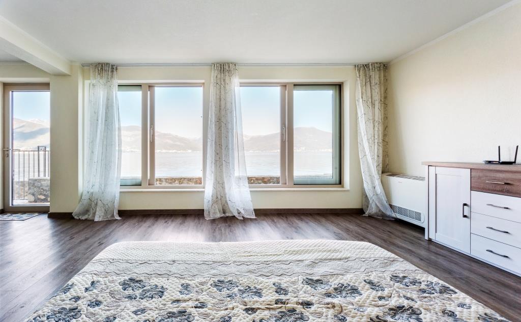 Bedroom with panoramic sea and mountain views in a villa, Krašići, Montenegro: bright interior, bed and dresser.