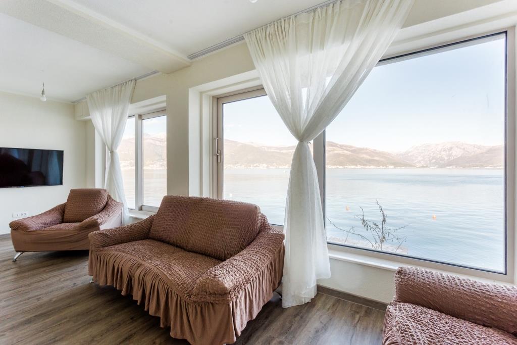 Living room with panoramic sea and mountain views in a villa, Krašići, Montenegro: soft furniture and a bright interior.