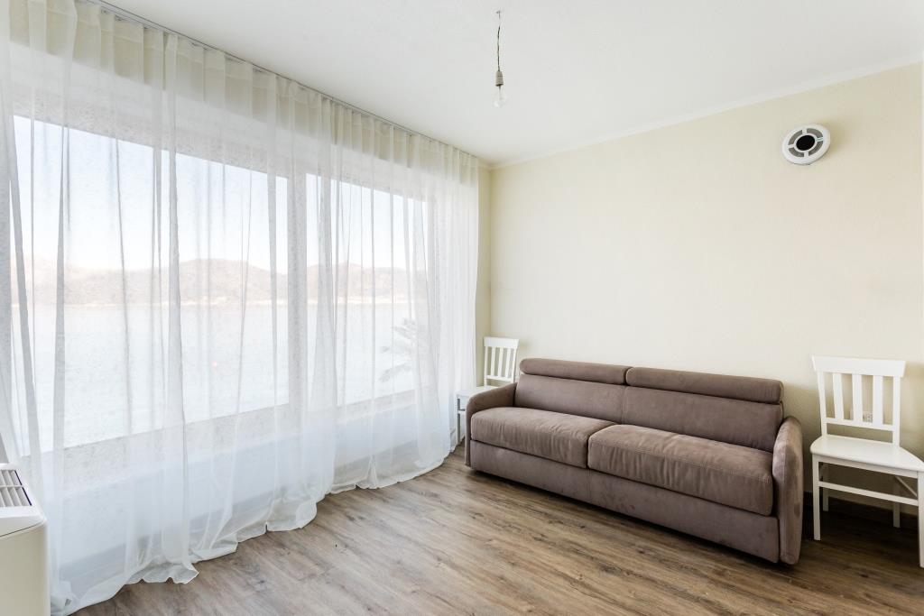 Living room with panoramic sea view in a villa, Krašići, Montenegro: brown sofa, light interior, and laminate flooring.