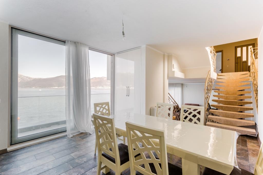 Living room with dining area and panoramic sea view in a villa, Krašići, Montenegro: light furniture and staircase.