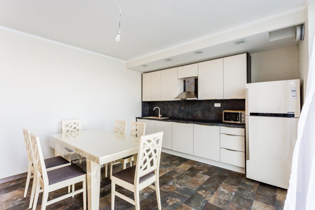 Modern kitchen with light cabinetry and a dining area in a villa in Krašići, Montenegro.