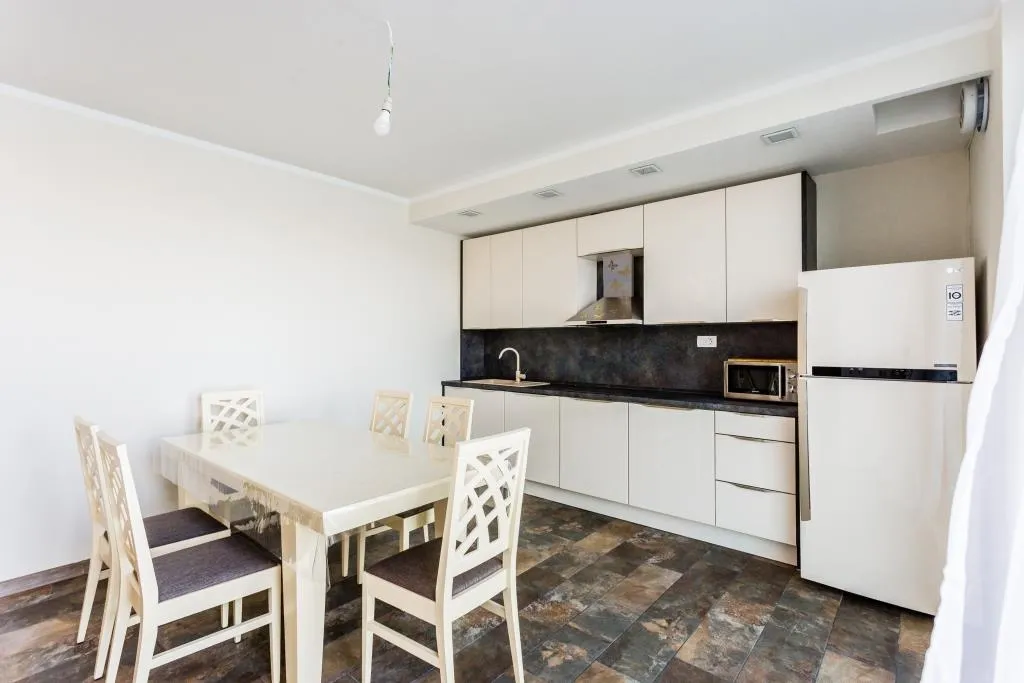 Modern kitchen with light cabinetry and a dining area in a villa in Krašići, Montenegro.