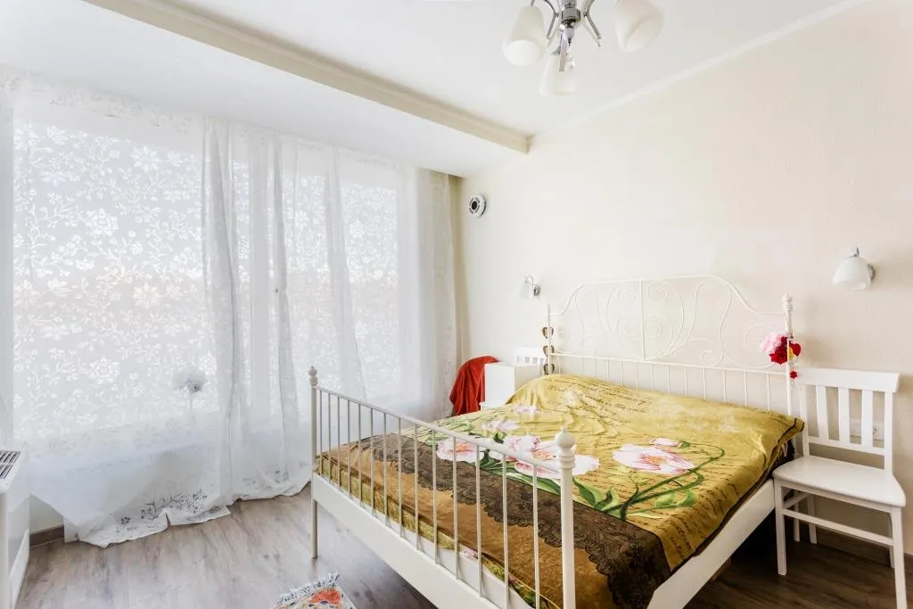 Bright bedroom with a white wrought-iron bed in a villa in Krašići, Montenegro: a cozy interior with a panoramic window.