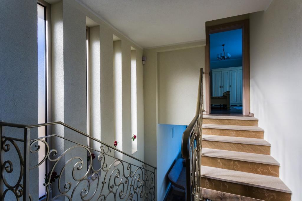 Staircase with wrought-iron railings and narrow windows in the interior of a villa in Krašići, Montenegro. View of a furnished bedroom.