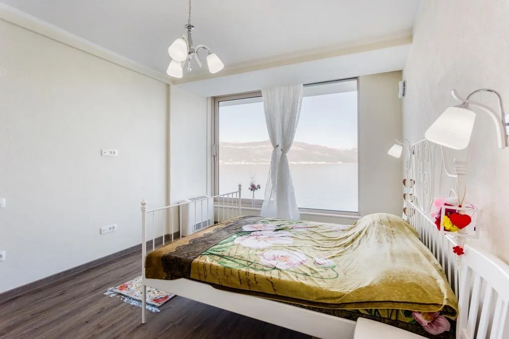 Bedroom with a double bed and panoramic sea view in a villa in Krašići, Montenegro.