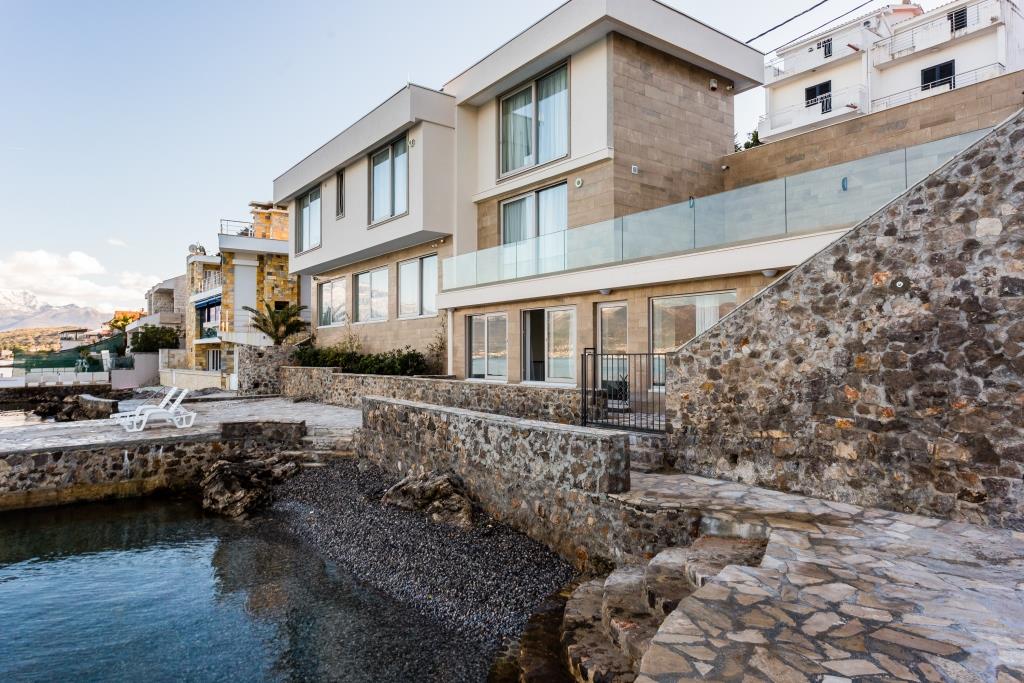 Modern villa on the seafront in Krašići, Montenegro: stone cladding, panoramic windows, and a private beach.