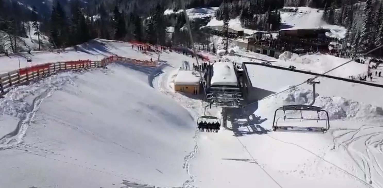 Vue de dessus d'une station de ski avec un télésiège et des pistes enneigées.