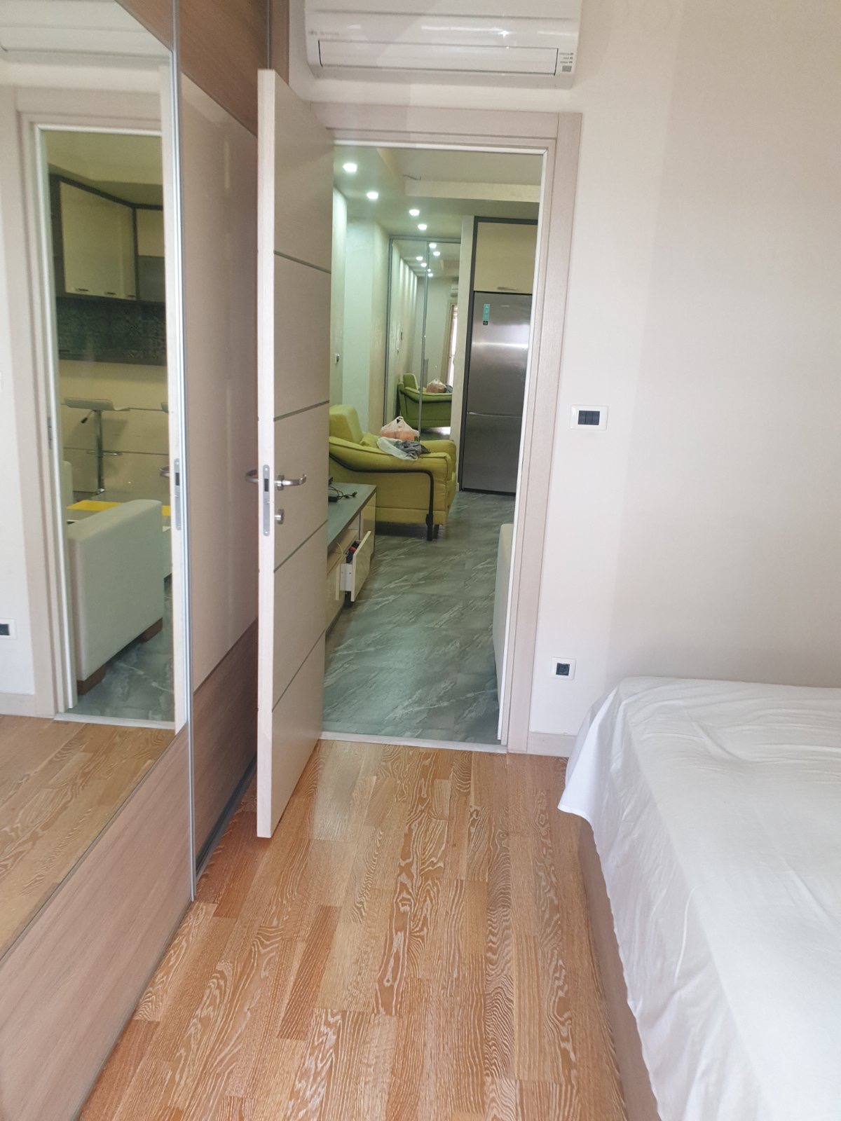 Schlafzimmer mit Spiegelschrank und Blick auf das Wohnzimmer in einer Wohnung in Budva, Montenegro: modernes Interieur und Parkett.