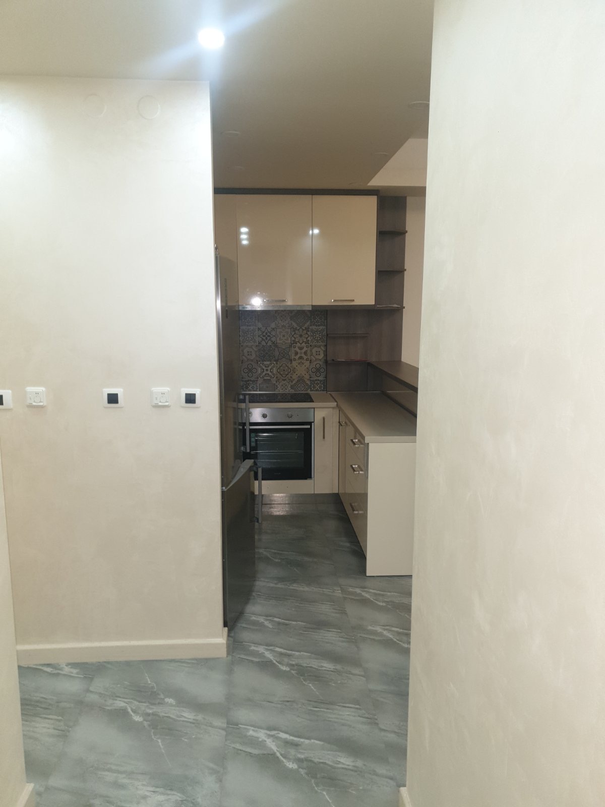 Moderne Küche in einer Wohnung in Budva, Montenegro: helle Einbauküche, integrierte Geräte und gemusterte Fliesen.