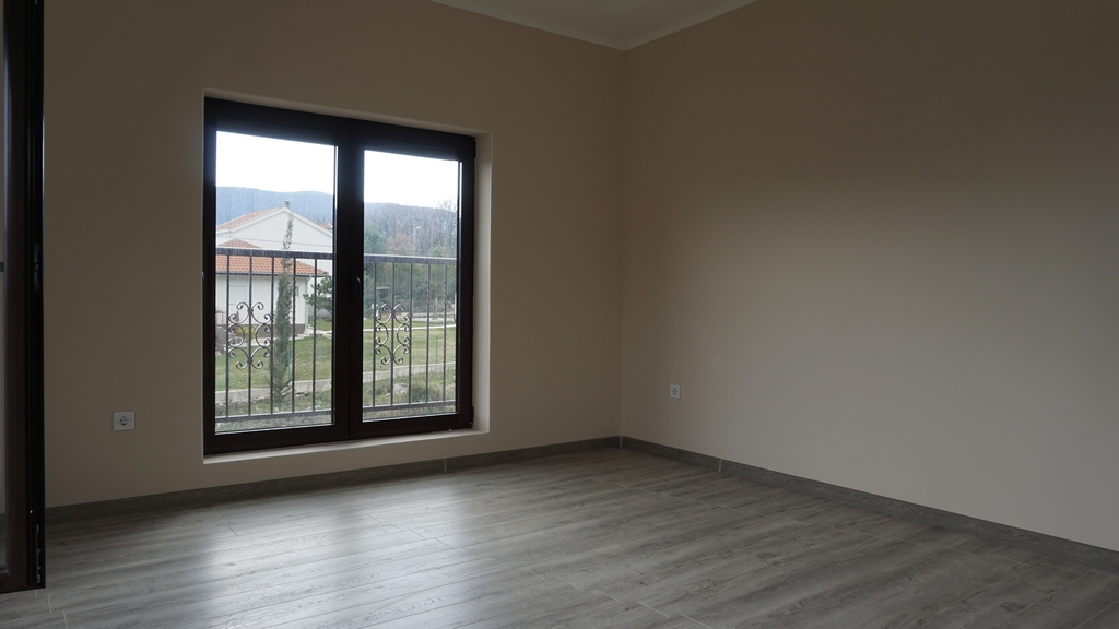 Salon lumineux avec parquet stratifié et baie vitrée panoramique dans une villa à Igalo, Herceg Novi, Monténégro.