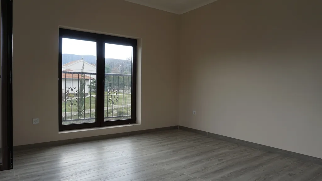 Salon lumineux avec parquet stratifié et baie vitrée panoramique dans une villa à Igalo, Herceg Novi, Monténégro.