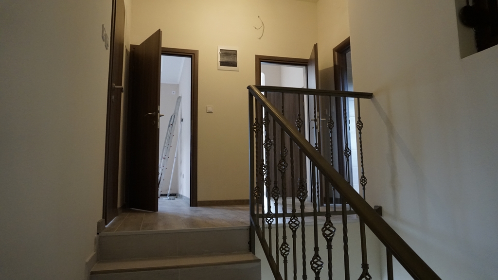 Intérieur d’une villa à Igalo, Monténégro : escalier avec rampe en fer forgé et pièces lumineuses avec portes intérieures.