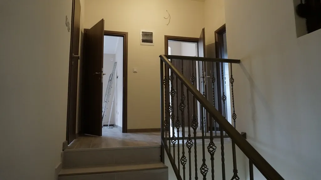 Intérieur d’une villa à Igalo, Monténégro : escalier avec rampe en fer forgé et pièces lumineuses avec portes intérieures.