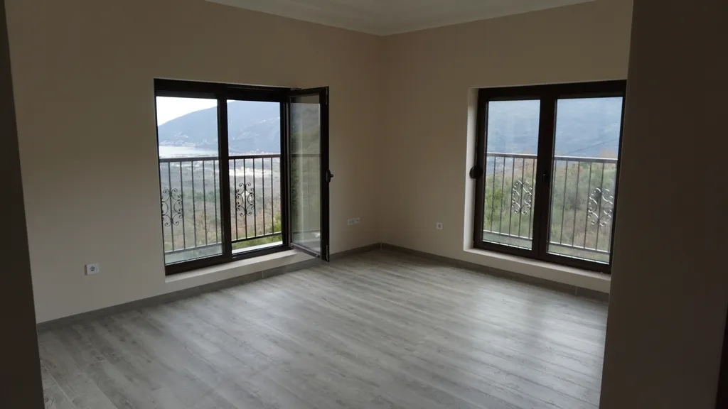 Salon lumineux avec parquet stratifié et vue panoramique sur les montagnes et la mer dans une villa, Igalo, Monténégro.