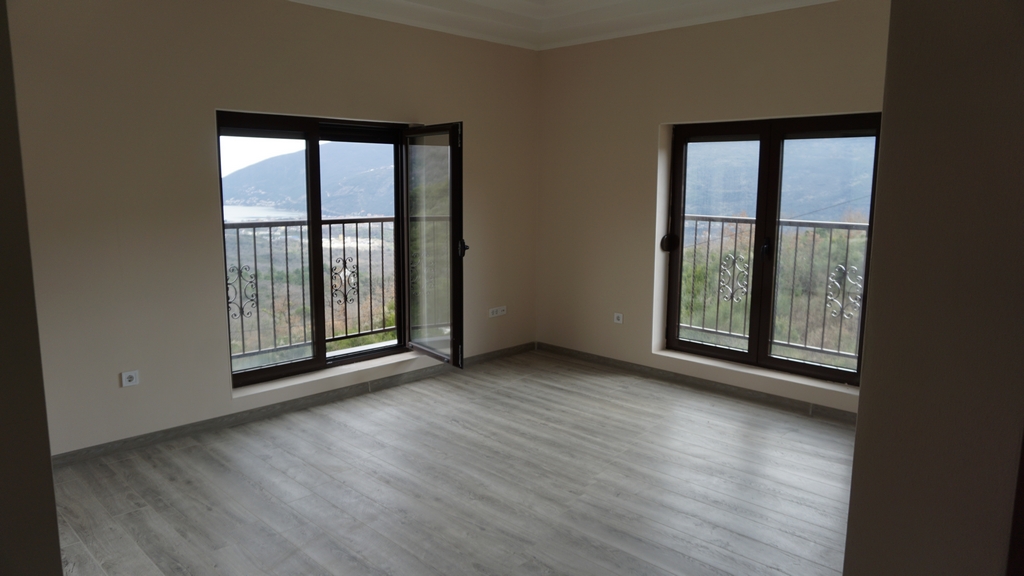 Salon lumineux avec parquet stratifié et vue panoramique sur les montagnes et la mer dans une villa, Igalo, Monténégro.