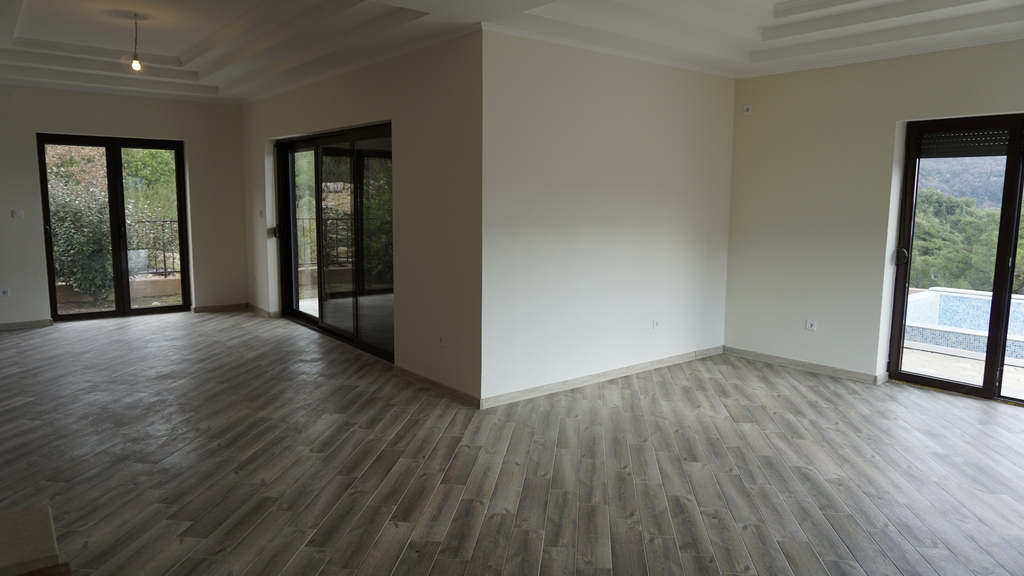 Salon spacieux avec baies vitrées panoramiques et accès à la piscine dans une villa à Igalo, Monténégro. Intérieur lumineux.