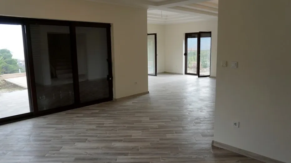 Salon spacieux avec baies vitrées panoramiques et finitions claires dans une villa à Igalo, Monténégro.