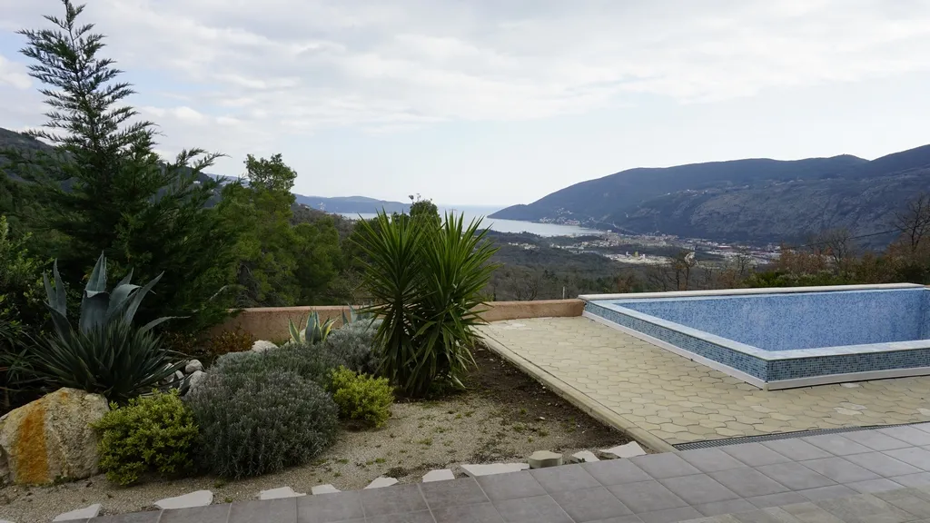 Piscine extérieure dans une villa à Igalo, Monténégro, avec vue panoramique sur les montagnes et la baie de Kotor, aménagement paysager.