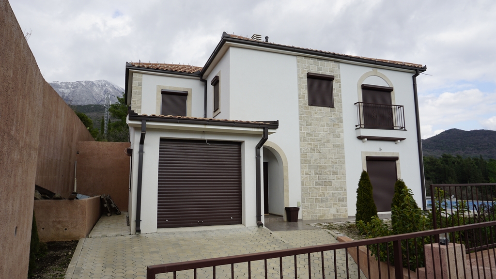 Villa à deux étages avec garage et façade en pierre à Igalo, Herceg Novi, Monténégro. Vue sur la maison et les montagnes.