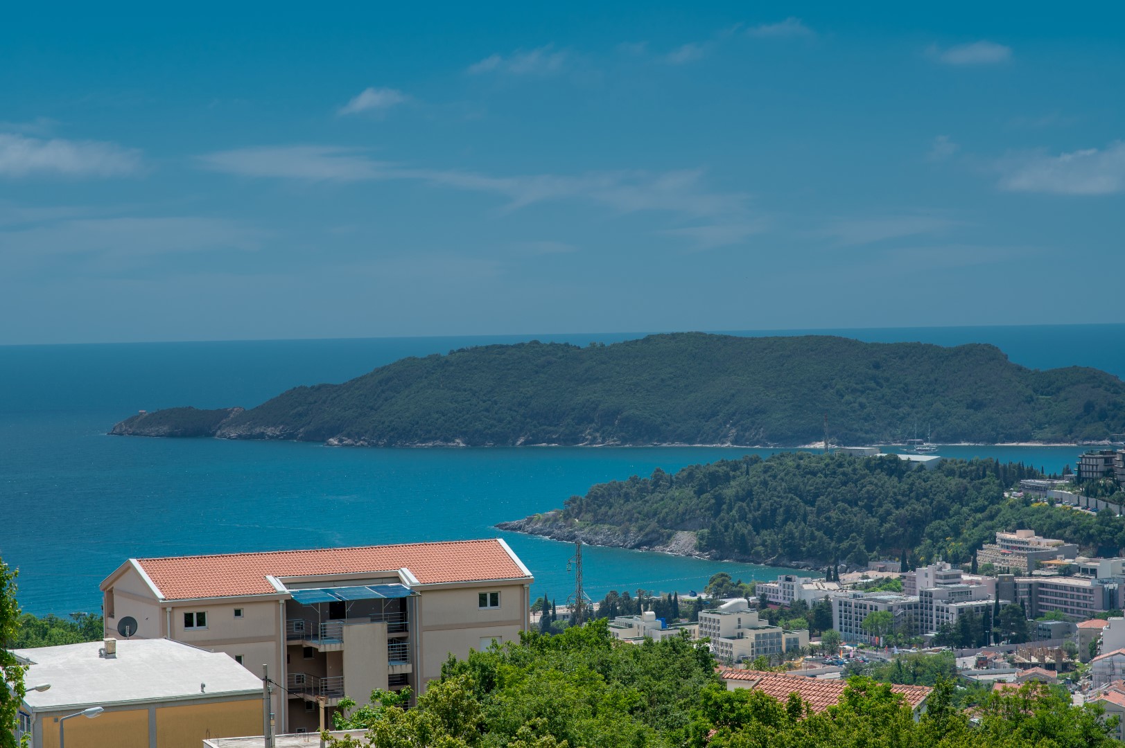 Panoramablick auf das Meer und die Insel St. Nikolaus von einer Villa in Bečići, Montenegro: Wohnhaus und Ferienlandschaft.