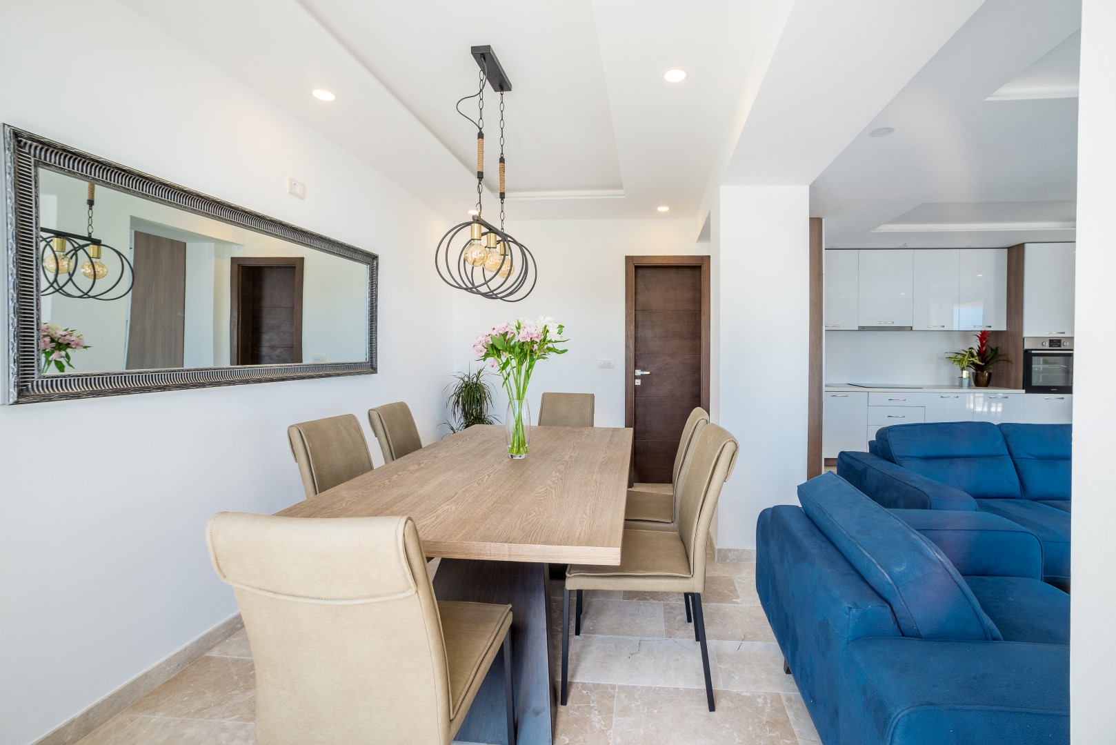 Modernes Wohnzimmer mit Essbereich und blauem Sofa in einer Villa in Bečići, Montenegro. Helles Interieur mit Spiegel.