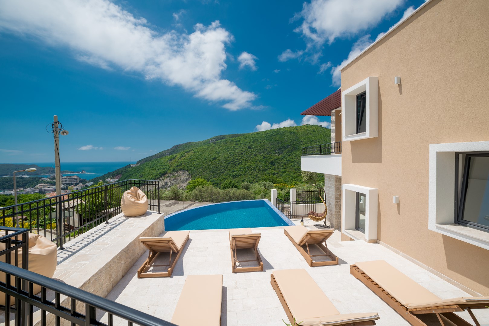 Villa in Bečići, Montenegro: Terrasse mit Pool, Sonnenliegen und Panoramablick auf die Berge und die Adria.
