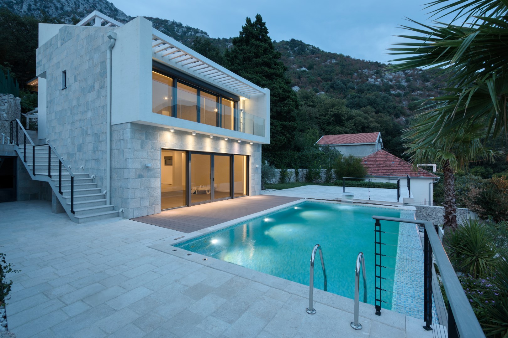 Karadağ, Strp köyünde havuzlu ve taş kaplamalı cepheye sahip modern villa, akşam dış görünüm.