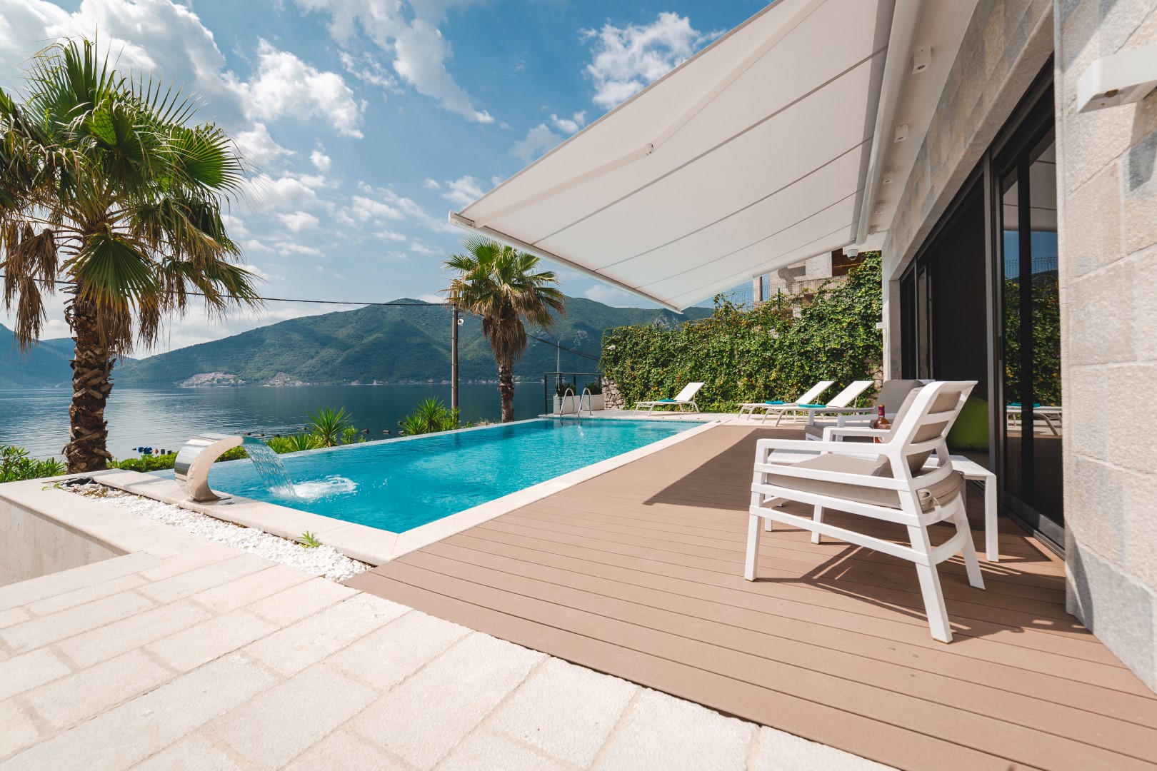 Strp, Karadağ'da villa: şelaleli havuz, şezlonglu teras ve deniz ile dağların panoramik manzarası.