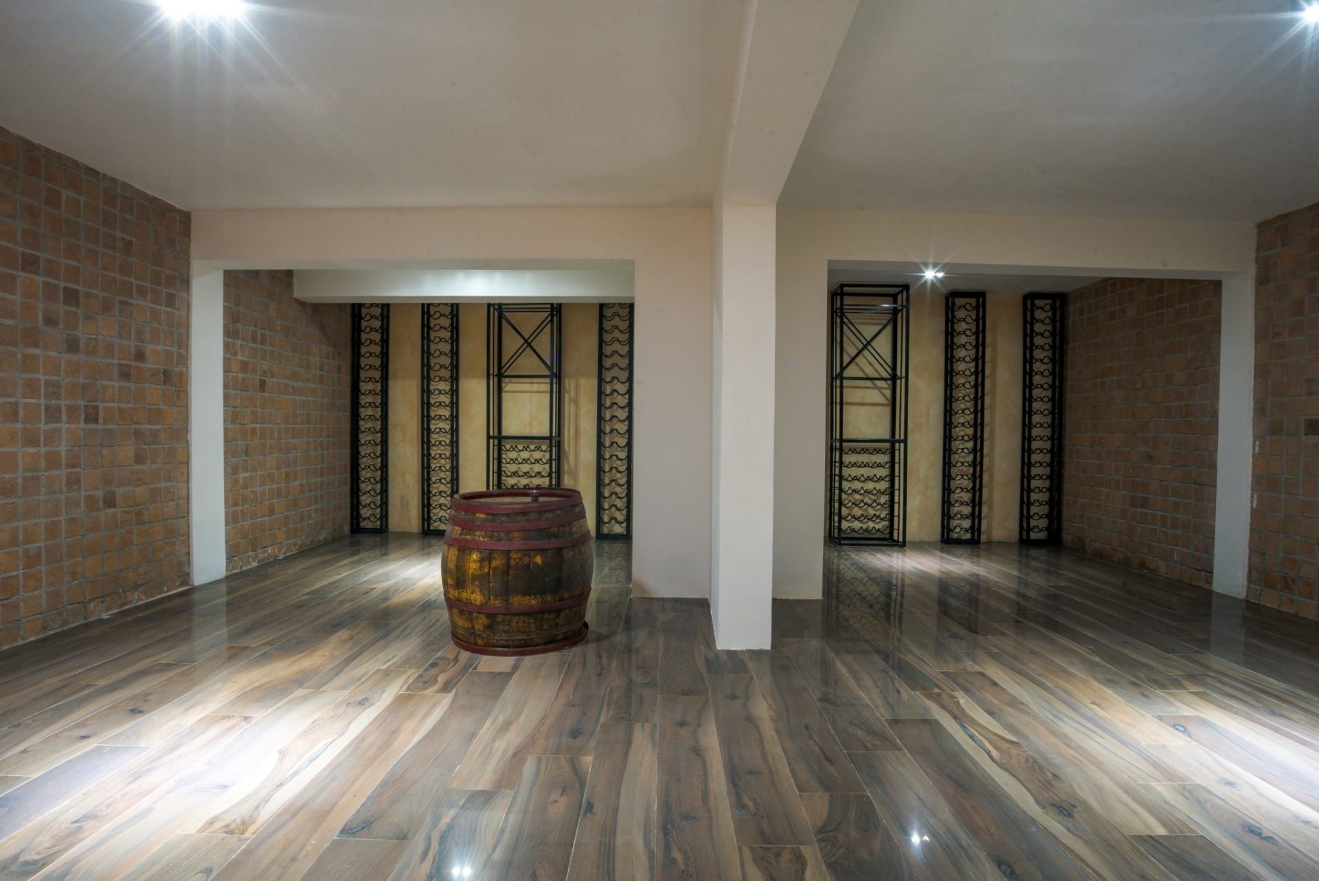 Weinkeller mit Holzfass und Regalen in einer exklusiven Villa in Budva, Montenegro, mit Ziegel- und Holzverkleidung.