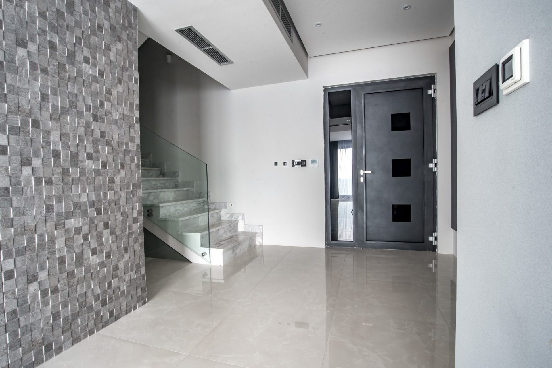 Modernes Interieur einer Villa in Budva, Montenegro: Marmortreppe mit Glasgeländer und stilvolle Eingangstür.