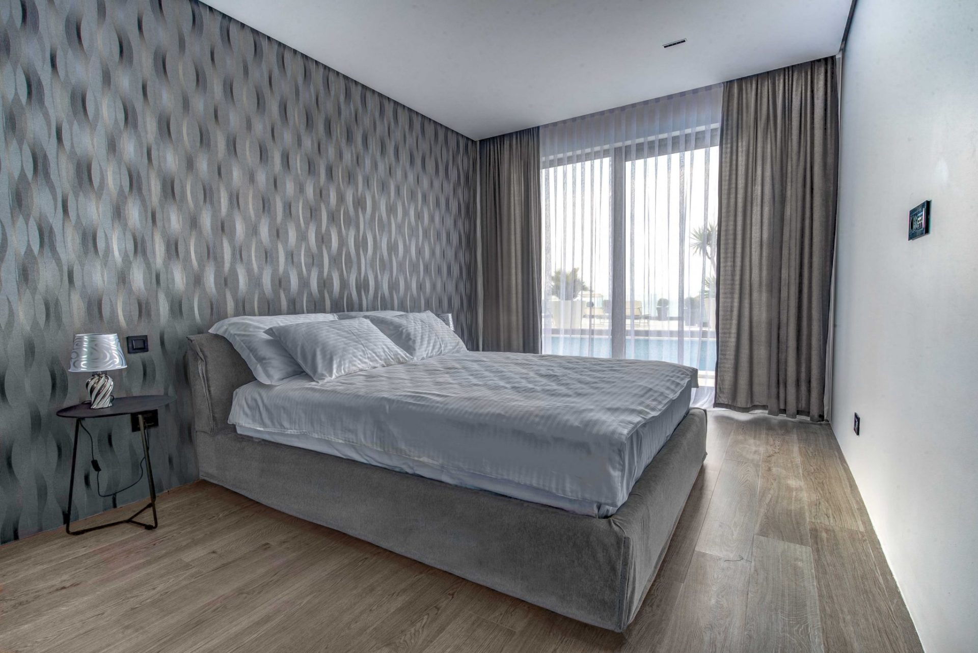 Modernes Schlafzimmer mit Doppelbett und Panoramafenster in einer Villa in Budva, Montenegro.