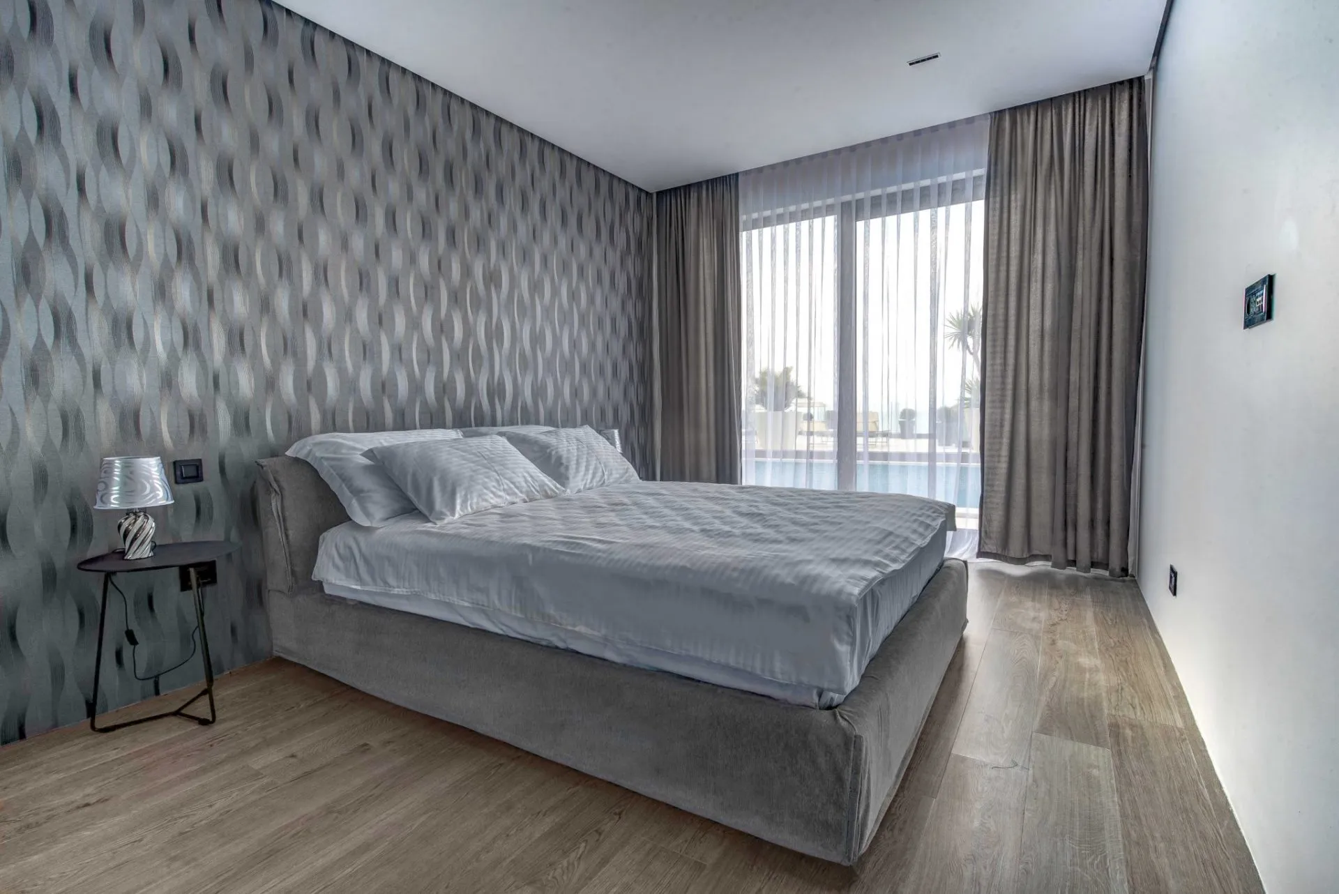 Modernes Schlafzimmer mit Doppelbett und Panoramafenster in einer Villa in Budva, Montenegro.
