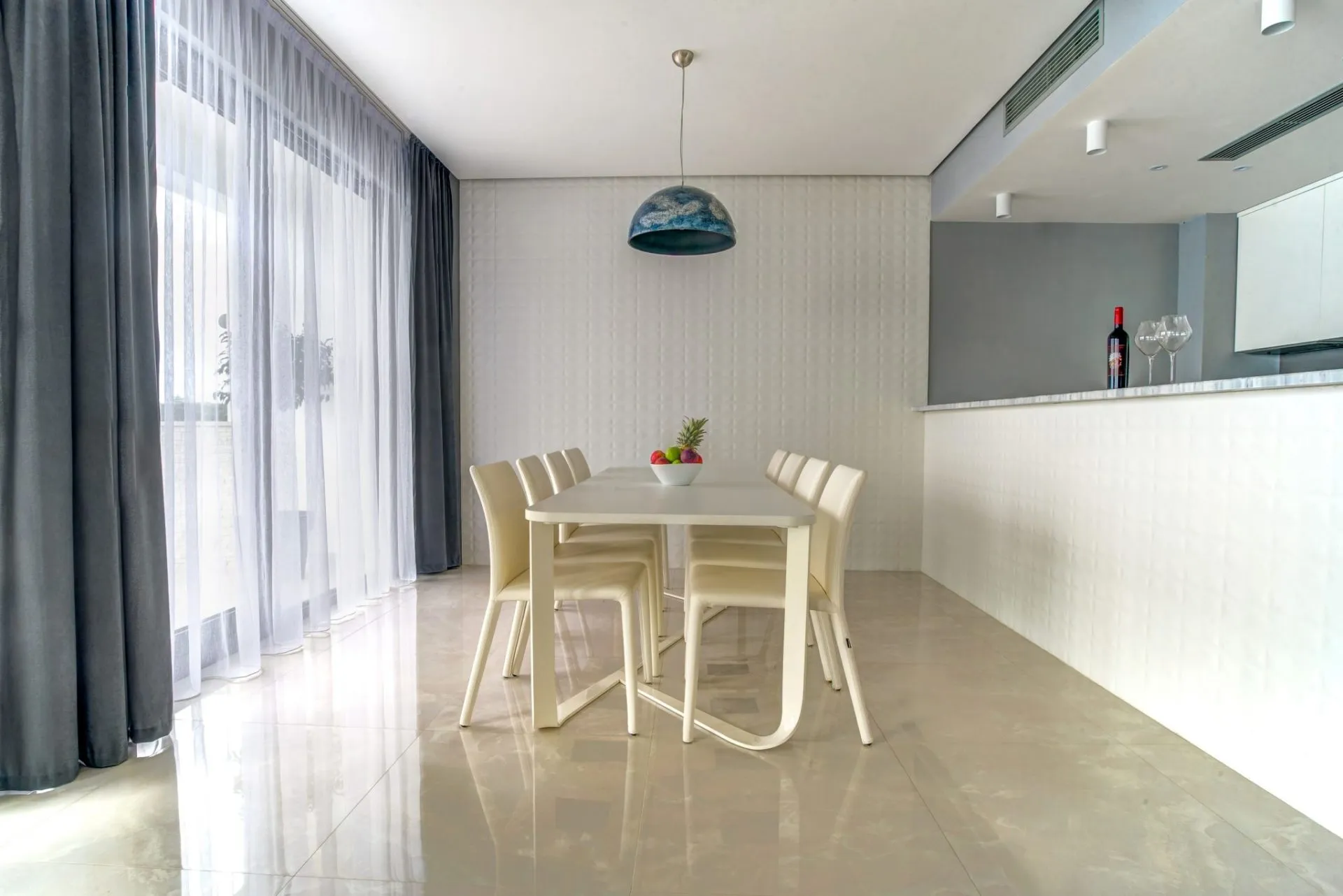 Moderner Essbereich mit weißem Tisch und Stühlen im Interieur einer Villa in Budva, Montenegro. Panoramafenster und Dekor.