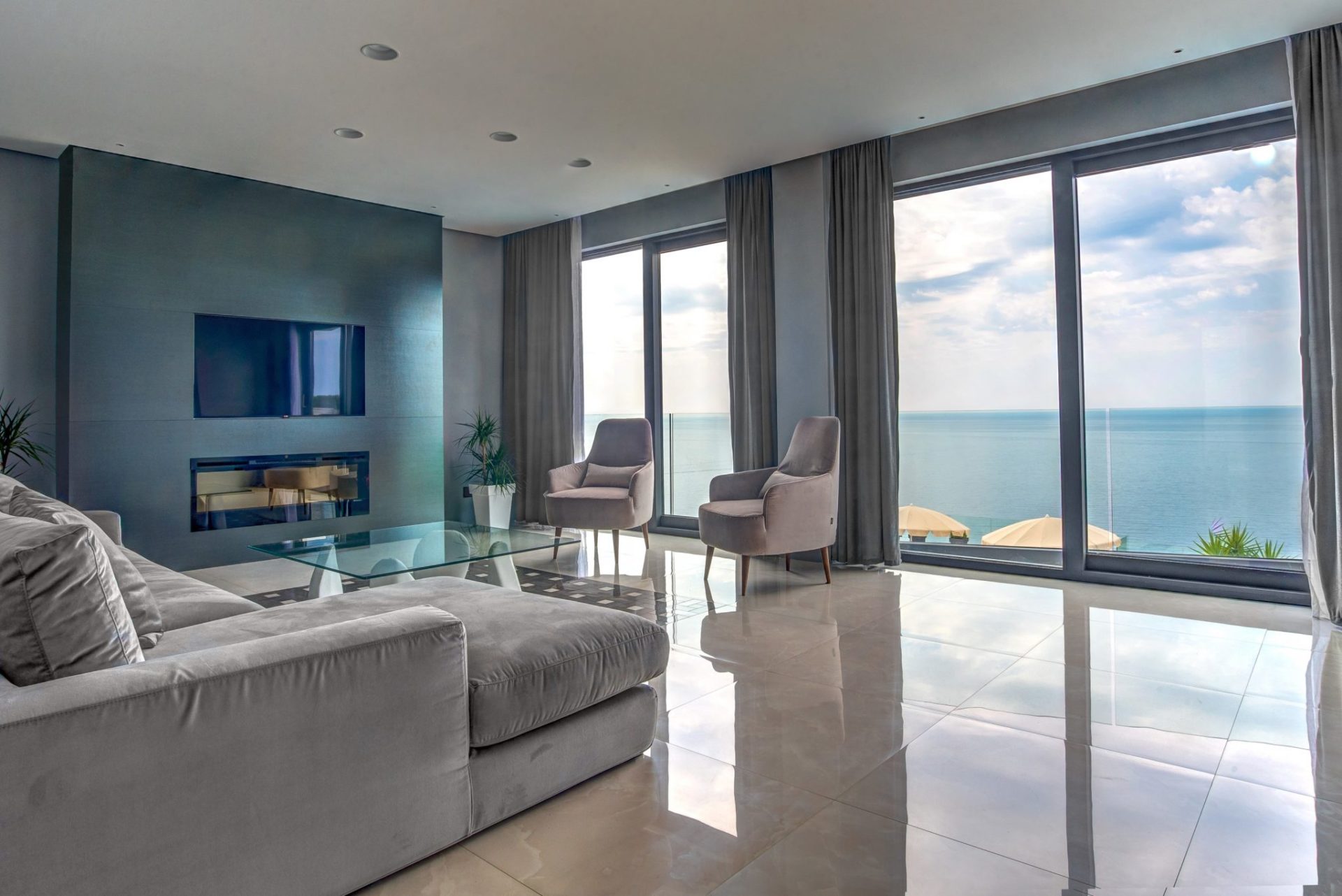 Wohnzimmer mit Panoramablick auf das Meer in einer exklusiven Villa, Budva, Montenegro: moderne Möbel, Kamin und Glastisch.