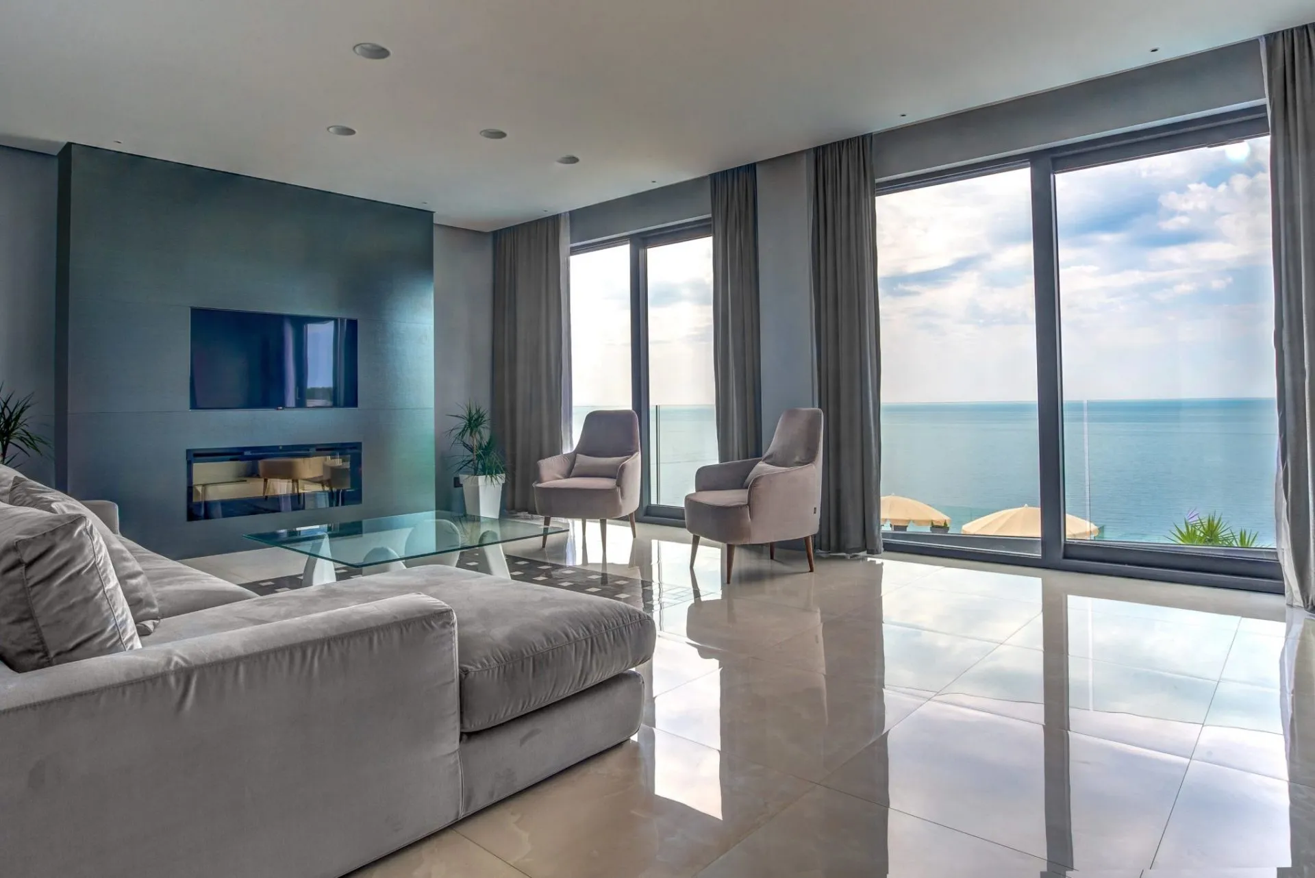 Wohnzimmer mit Panoramablick auf das Meer in einer exklusiven Villa, Budva, Montenegro: moderne Möbel, Kamin und Glastisch.