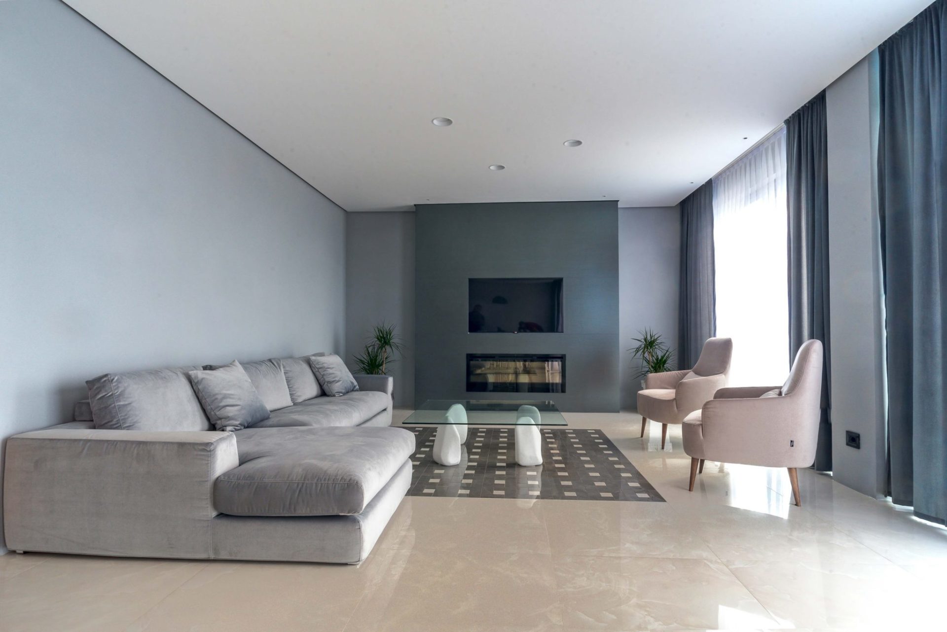 Modernes Wohnzimmer mit grauem Sofa, Kamin und TV in einer exklusiven Villa in Budva, Montenegro. Stilvolles Interieur mit Panoramafenstern...