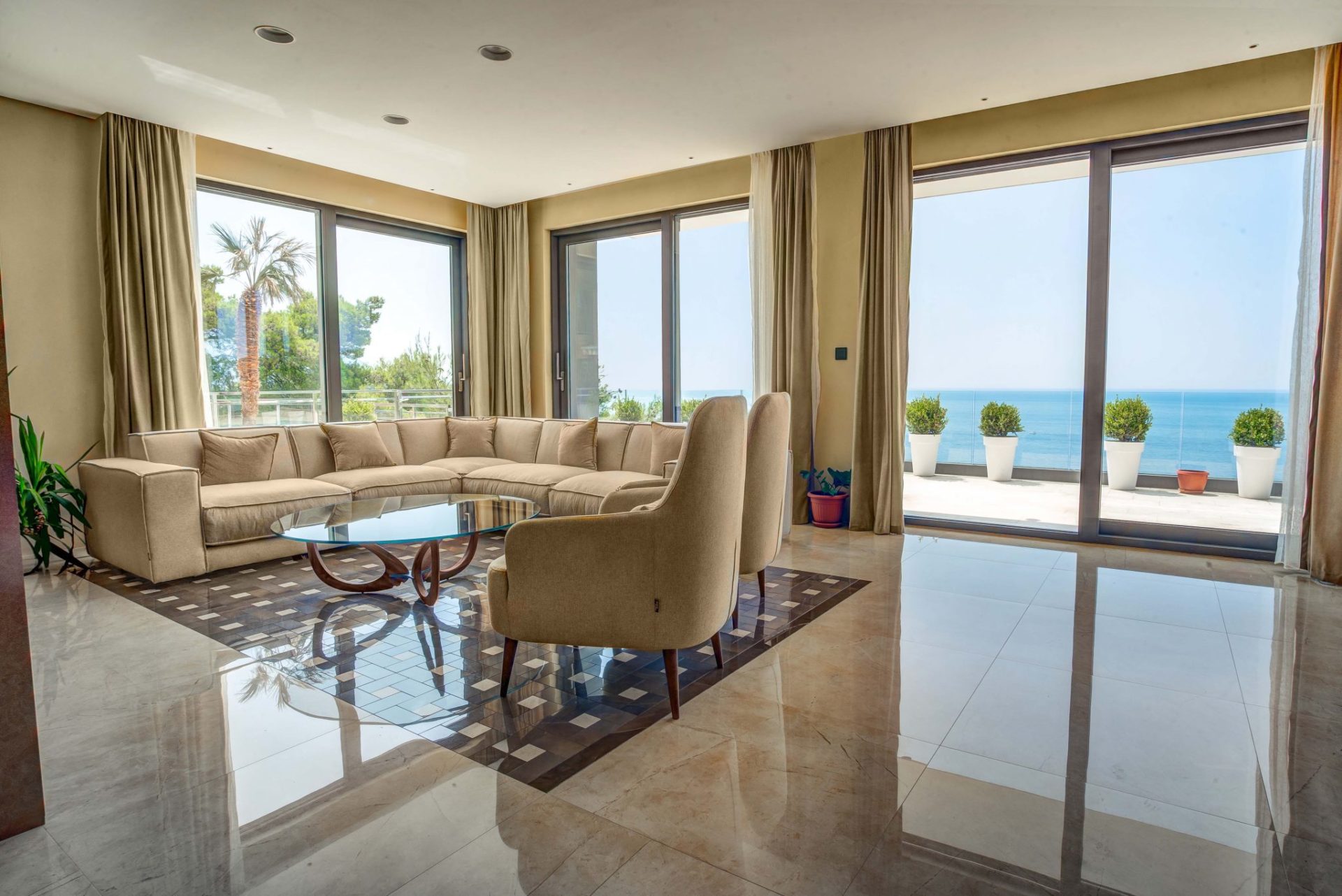 Wohnzimmer mit Panoramablick auf das Meer und Terrasse in einer Villa in Budva, Montenegro: helle Möbel und Marmorboden.