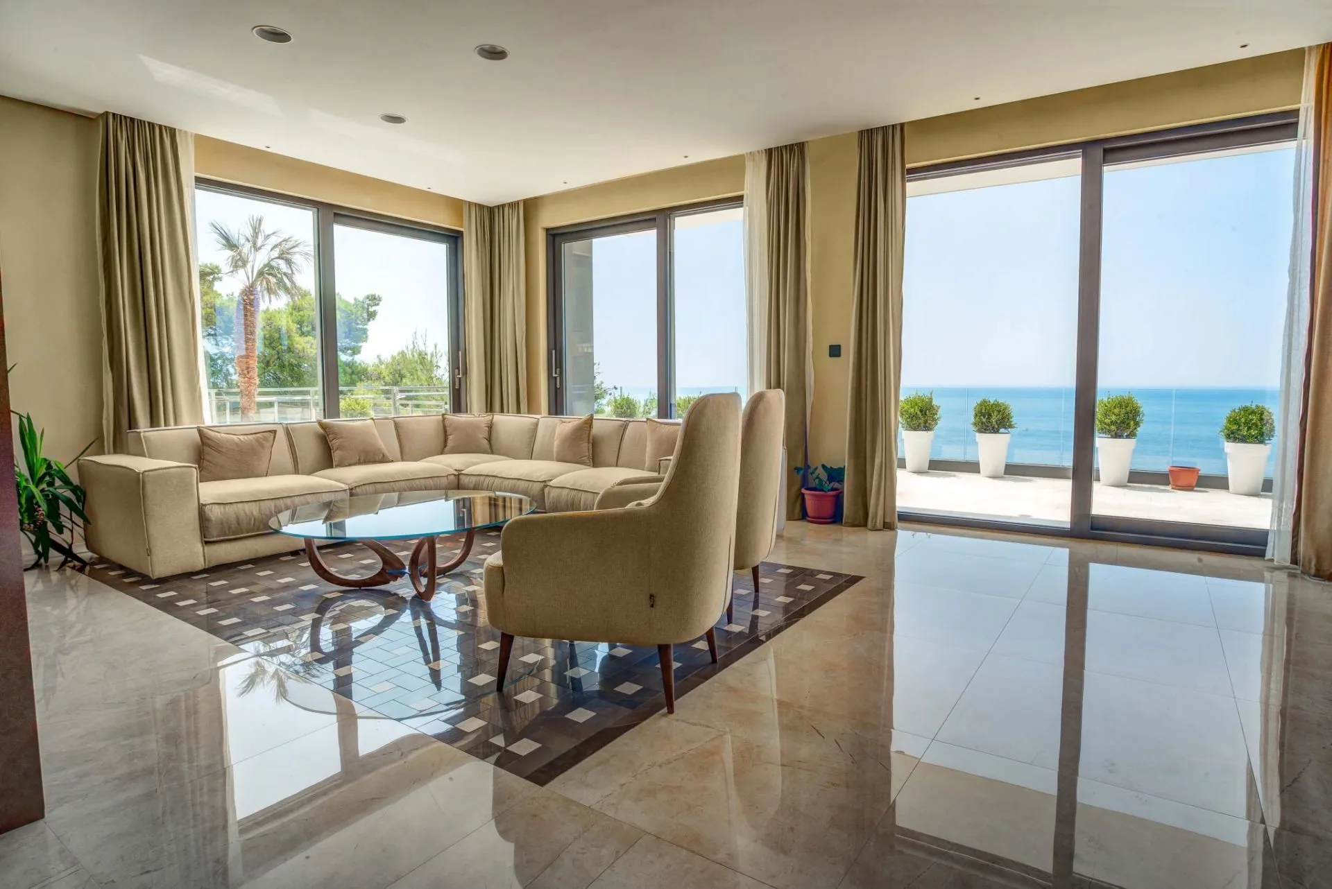 Wohnzimmer mit Panoramablick auf das Meer und Terrasse in einer Villa in Budva, Montenegro: helle Möbel und Marmorboden.