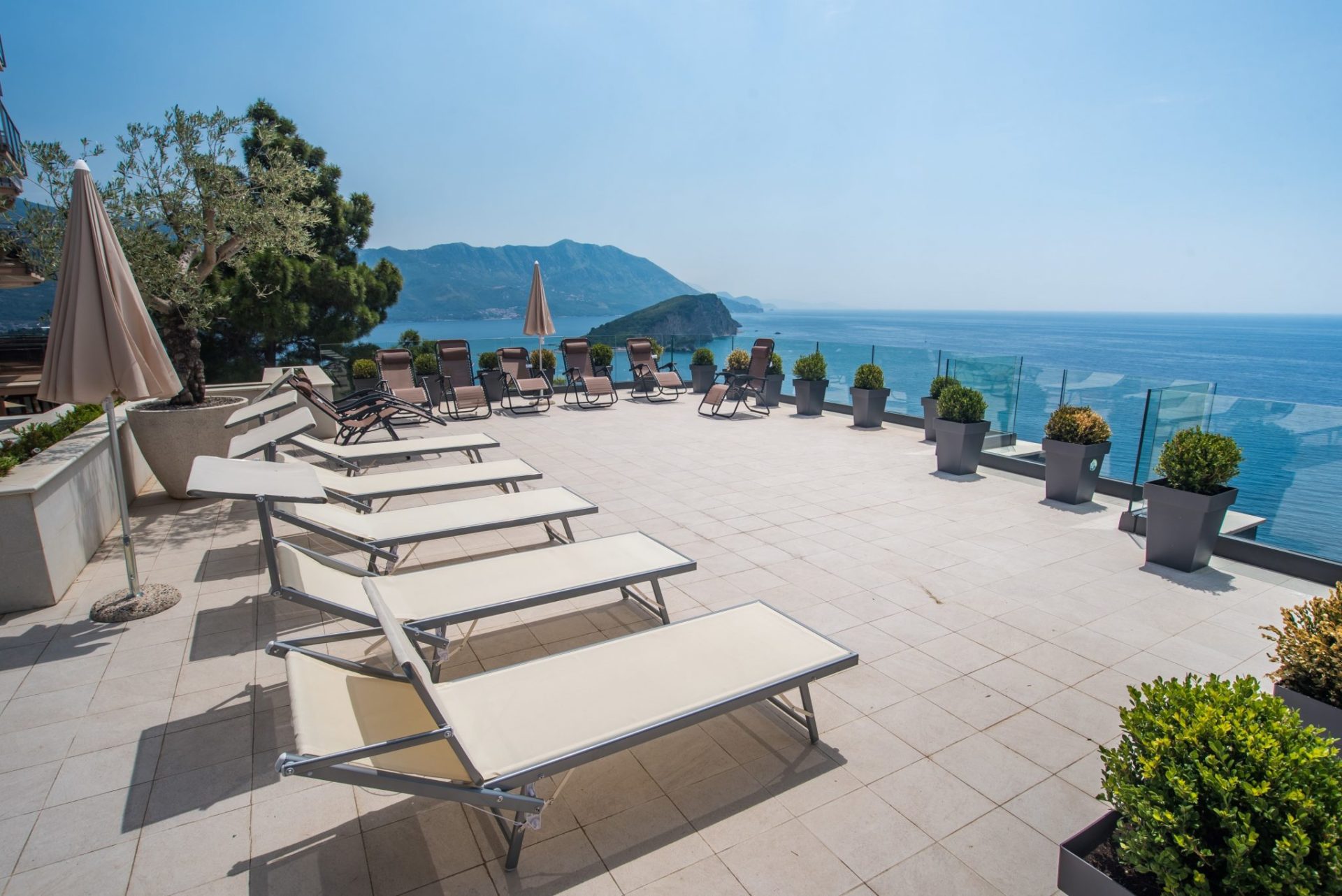Terrasse mit Liegestühlen und Panoramablick auf das Meer und die Insel in Budva, Montenegro. Moderne Villa mit Ruhebereich.