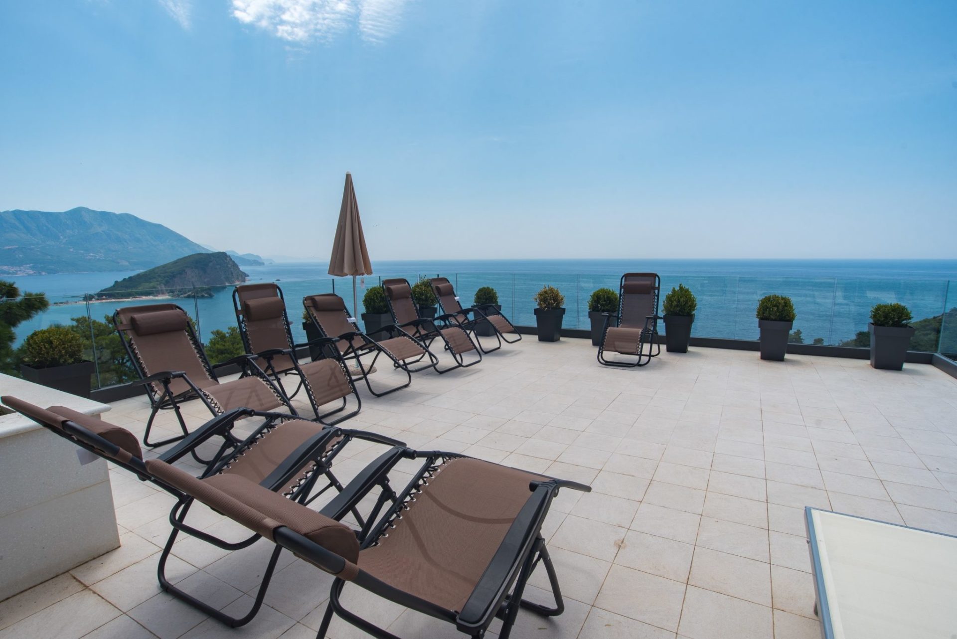 Terrasse mit Liegestühlen und Panoramablick auf das Meer und die Insel in Budva, Montenegro. Moderne Villa mit Ruhebereich.