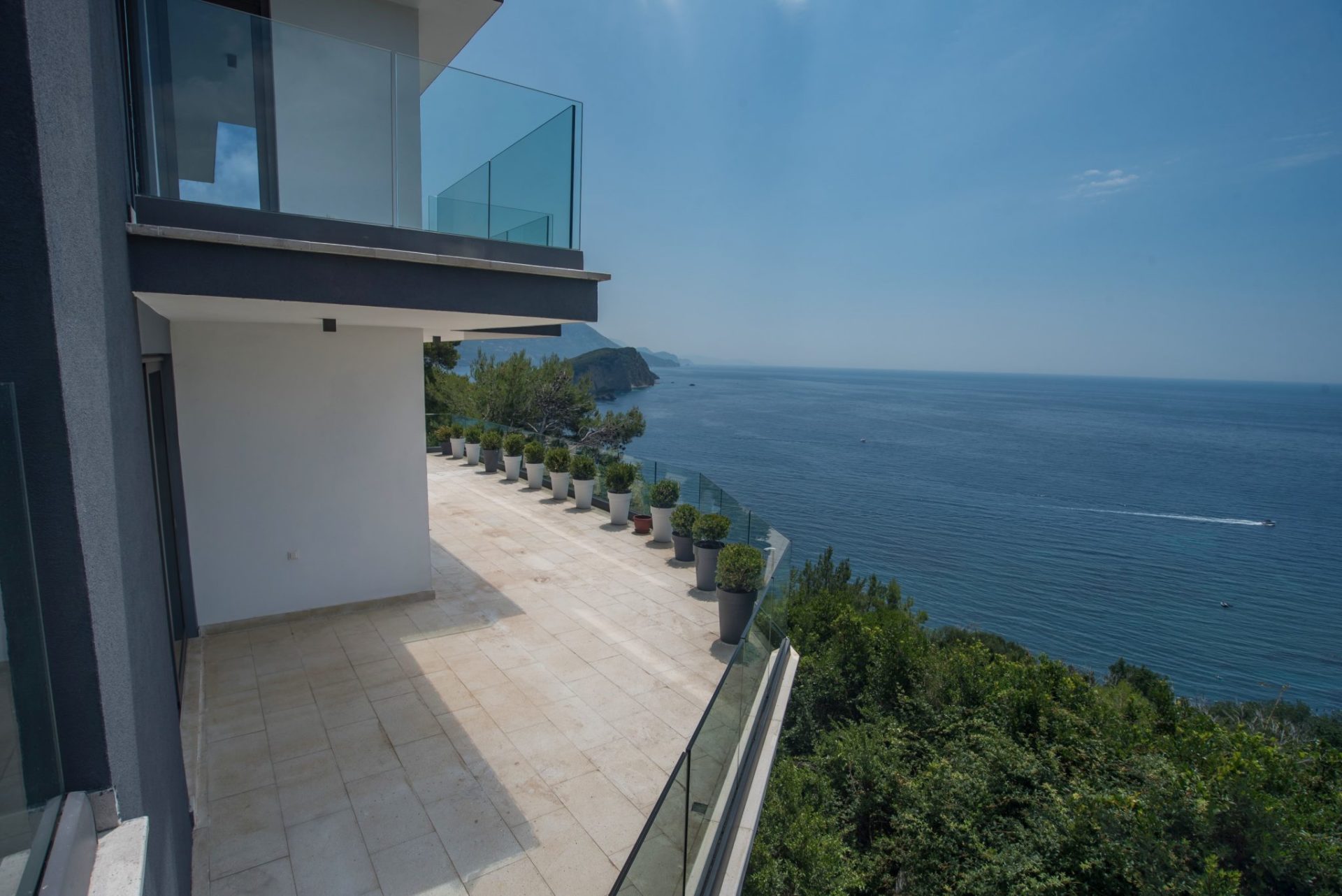 Geräumige Terrasse einer modernen Villa in Budva, Montenegro, mit Panoramablick auf das Meer und Glasgeländer.